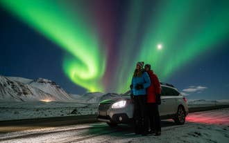 Paar bewundert die Nordlichter mit seinem Mietwagen