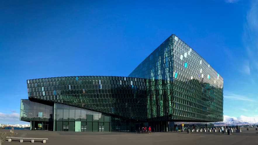 Harpa Koncertsal i Reykjavik i Island med en glasfacade, der reflekterer himlen på en solrig dag.
