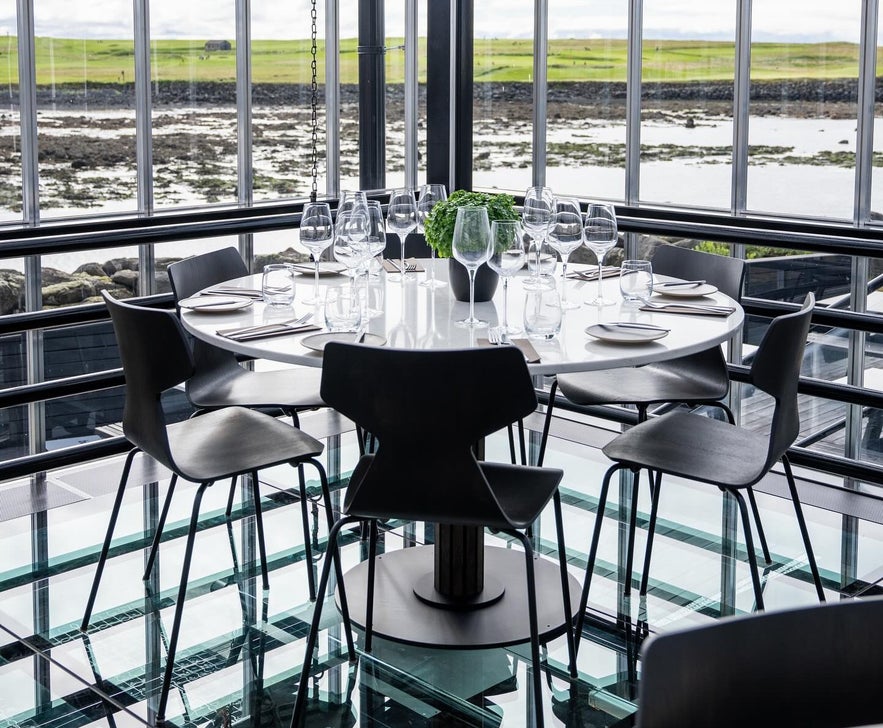 Glass-walled dining area at Sól Restaurant near Reykjavik, with modern decor and natural light creating a bright, stylish atmosphere.