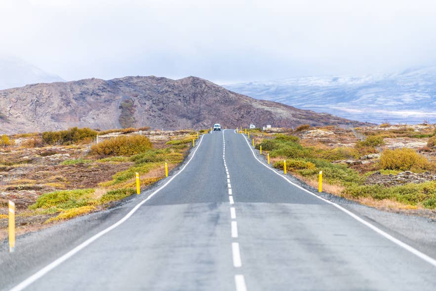 Scenic drive to Thingvellir National Park in Iceland with a single car on the Ring Road through volcanic landscapes.