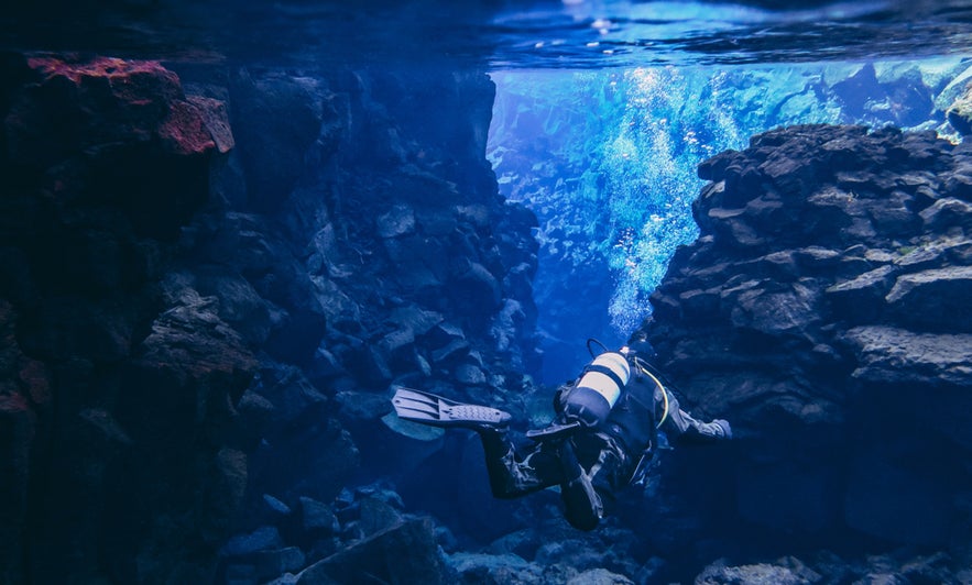 Scuba diver exploring Silfra Fissure in Thingvellir National Park, Iceland, between North American and Eurasian plates.