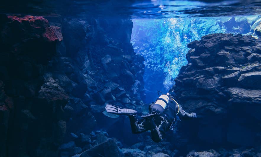 Scuba diver exploring Silfra Fissure in Thingvellir National Park, Iceland, between North American and Eurasian plates.