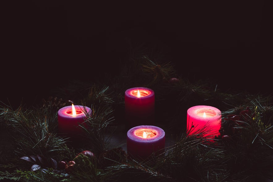Four red Advent candles lit with pine wreath decoration, symbolizing the festive traditions of Christmas in Iceland.