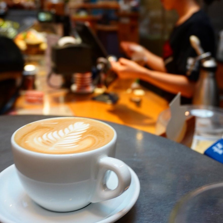 Close-up of a cup of coffee with leaf latte art in a Reykjavik café, perfect for warming up while exploring the city in October.