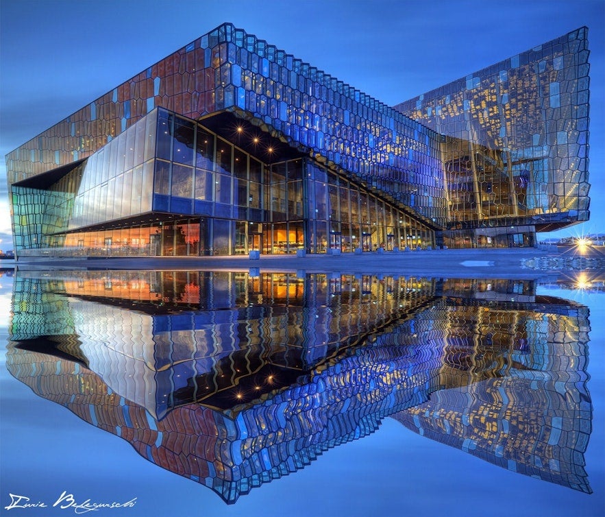 Harpa Concert Hall in Reykjavik at night, fully reflected on water, a top spot for experiencing world-class performances in October.