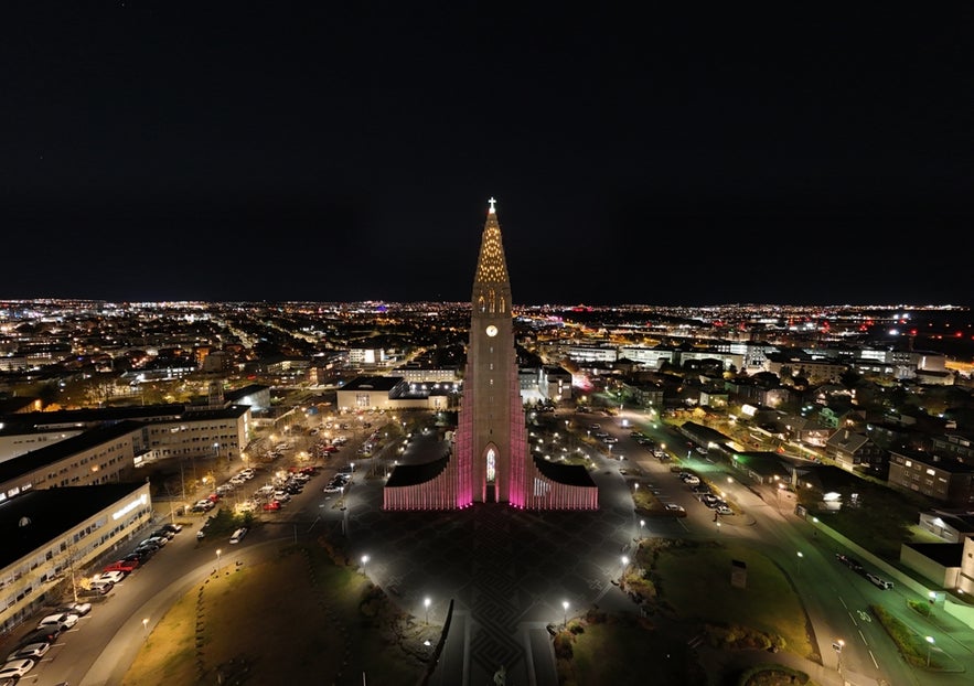 Aerial view of Hallgrimskirkja in Reykjavik illuminated in pink for Breast Cancer Awareness Month, highlighting the city’s support for the cause in October.