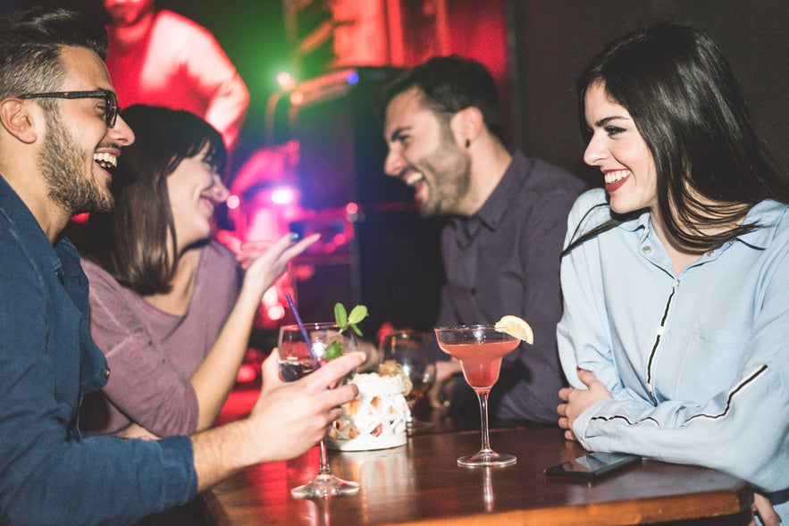 Happy friends enjoying cocktails at a bar in Reykjavik.