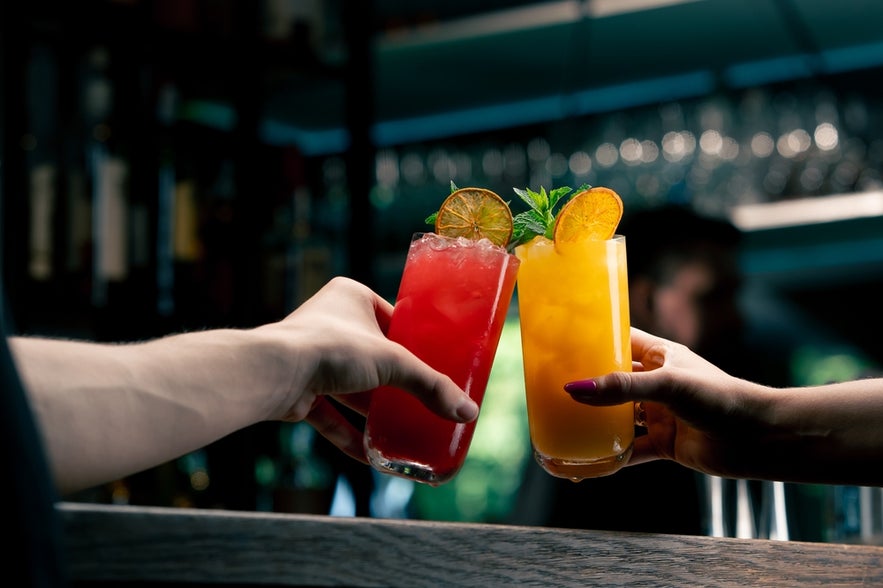Close up of two people cheering cocktails in a bar in Reykjavik.