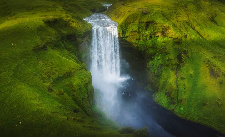 Wodospad Skogafoss spływający po zielonych klifach w południowej Islandii.