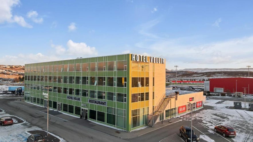 Exterior of Hotel Vellir, a green building featuring many windows, one of the best places to stay in Hafnarfjordur, Iceland.