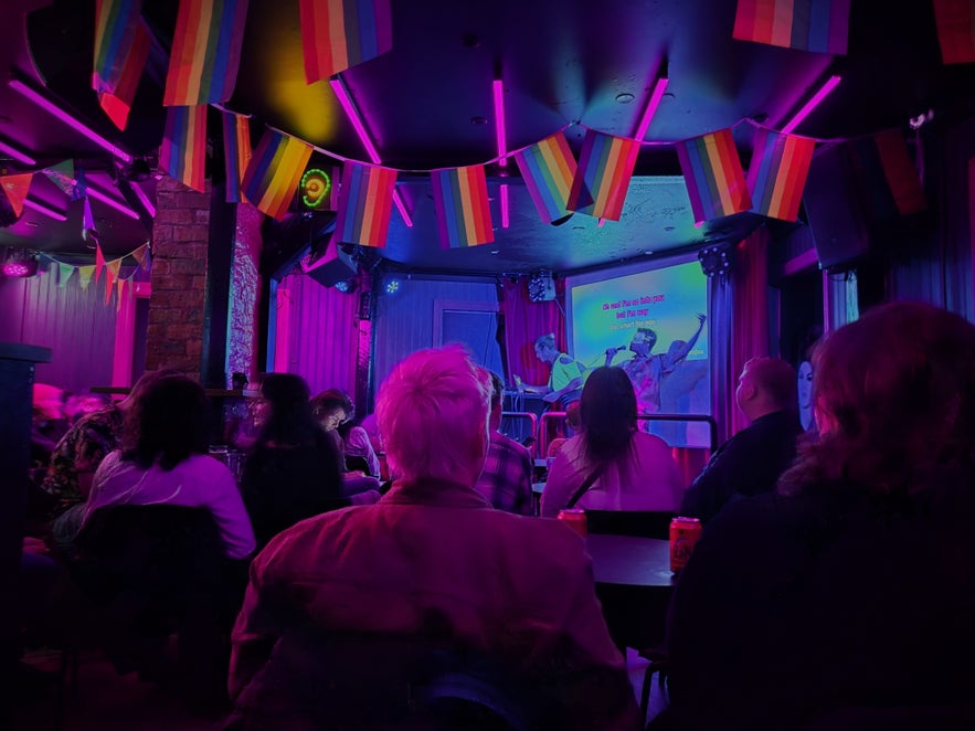 Karaoke night crowd at Kiki Bar Reykjavik with rainbow flags and stage lighting.
