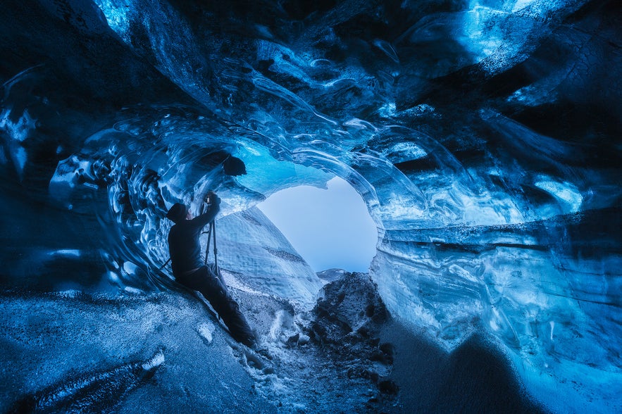 Inside Katla Ice Cave in Iceland, with striking blue glacier walls and light shining through the ice tunnel.