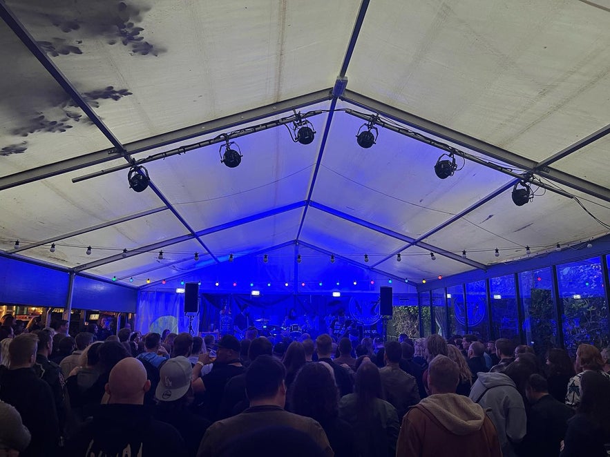Crowd enjoying a live music concert at Lemmy Bar in Reykjavik, Iceland, with stage lights and performances in an outdoor tent venue.