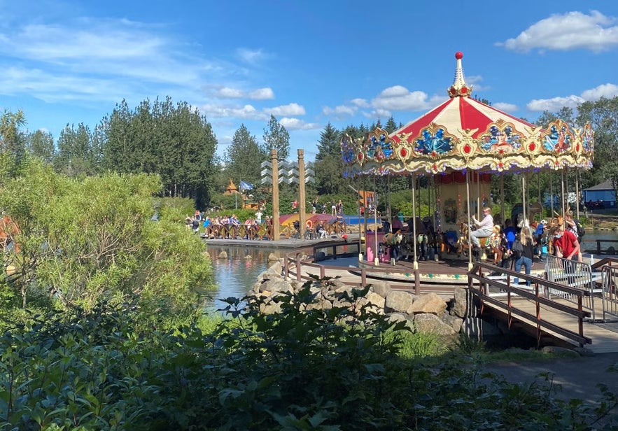 Carousel by a lake in a family outdoor park in Reykjavik on a sunny day.