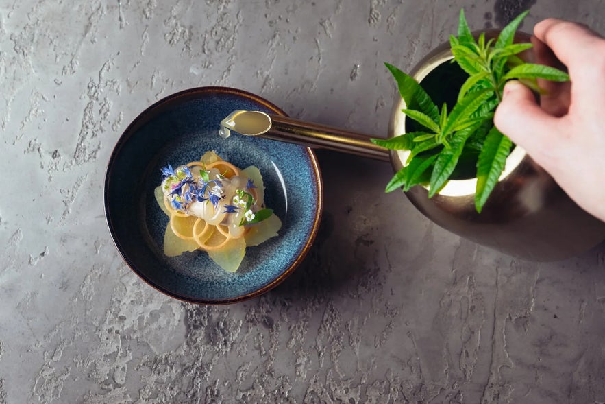 Gourmet plated dish with fresh herbs being prepared in a restaurant during the Food and Fun Festival in Reykjavik.