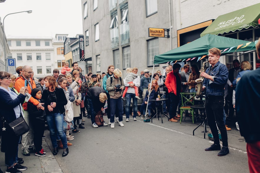 A street musician playing saxophone surrounded by people during an outdoor event at Reykjavik Culture Night.