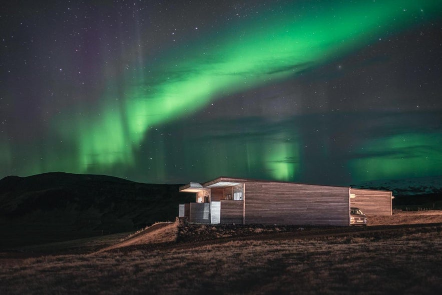 Northern lights dancing above Black Beach Suites at night, highlighting Iceland’s beauty. Northern lights dancing above Black Beach Suites at night, highlighting Iceland’s beauty.