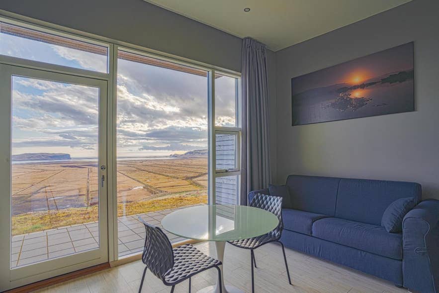 Interior view from Black Beach Suites with modern decor, glass doors, and stunning views of Iceland's South Coast.
