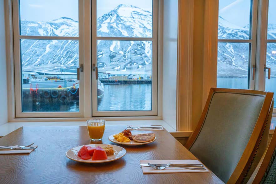 Colazione con vista sul porto e sulle montagne innevate dalla sala da pranzo del Siglo Hotel a Siglufjörður, in Islanda.
