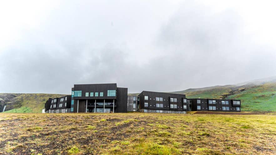 Exterior of Fosshotel Glacier Lagoon, a sleek black hotel set against Iceland’s dramatic green hills and waterfalls. Exterior of Fosshotel Glacier Lagoon, a sleek black hotel set against Iceland’s dramatic green hills and waterfalls.