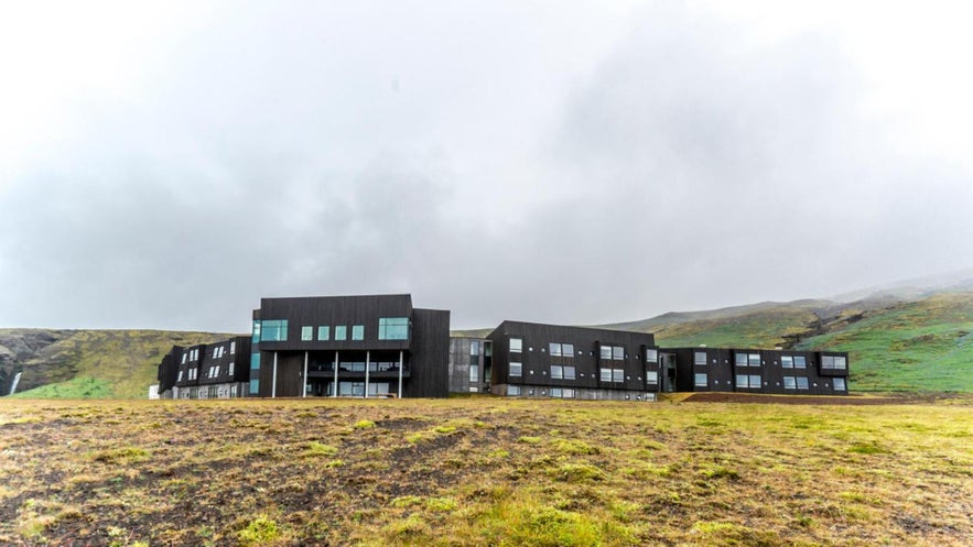 Exterior of Fosshotel Glacier Lagoon, a sleek black hotel set against Iceland’s dramatic green hills and waterfalls. Exterior of Fosshotel Glacier Lagoon, a sleek black hotel set against Iceland’s dramatic green hills and waterfalls.