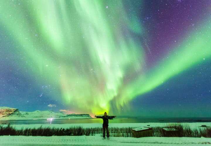 Northern Lights over snowy mountains and sea during Christmas in Iceland