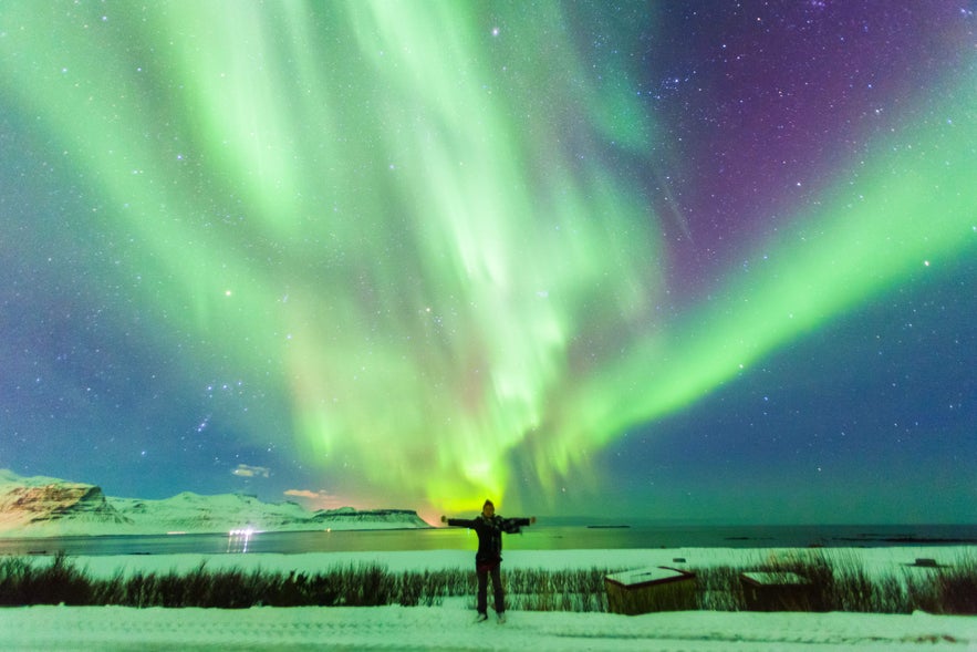 Northern Lights over snowy mountains and sea during Christmas in Iceland
