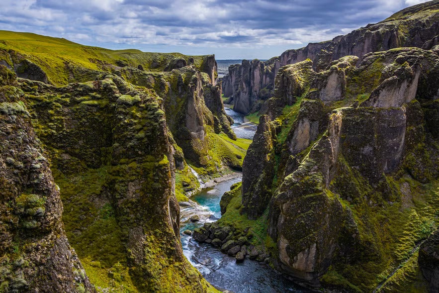 Fjadrargljufur canyon in South Iceland with a river flowing between mossy cliffs.