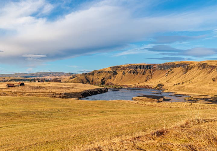 Scenic river valley near Kirkjubaejarklaustur in South Iceland with golden hills and scattered farms.
