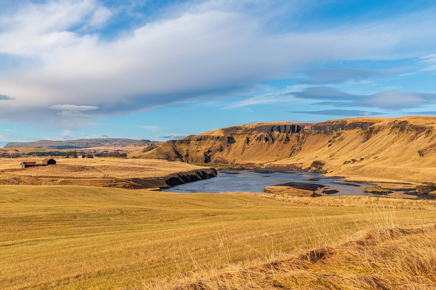 Scenic river valley near Kirkjubaejarklaustur in South Iceland with golden hills and scattered farms.