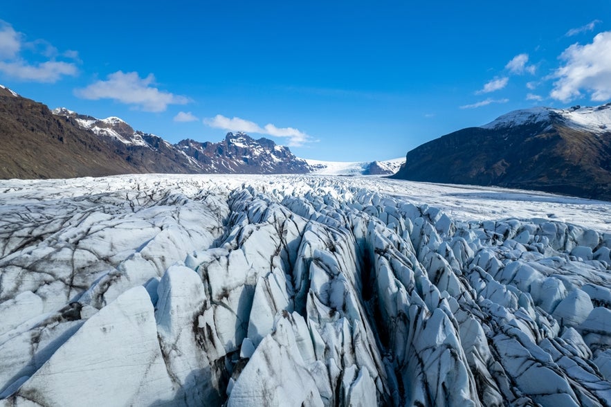 A close-up view of the Svinafellsjokull glacier in Vatnajökull National Park, Iceland, shows deep crevasses and textured ice.