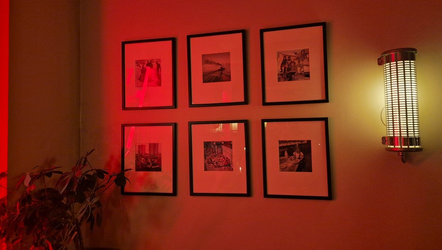 Wall art display with framed photographs and red lighting inside Litli Barinn in Reykjavik.