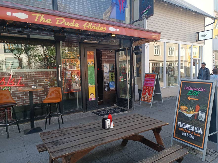 Entrance of Lebowski Bar in Reykjavik, themed after The Big Lebowski movie, with happy hour deals advertised outside.