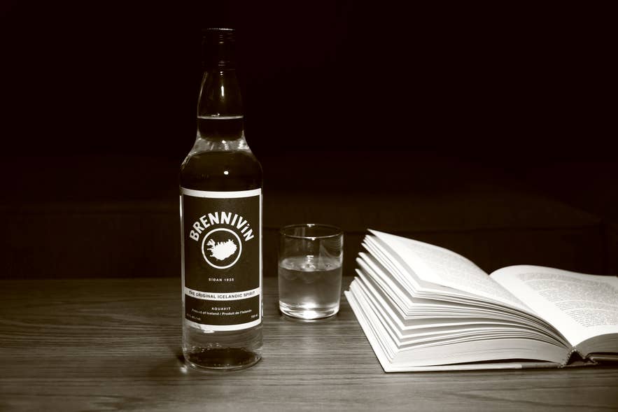 Bottle of Brennivín schnapps with a glass and book, showcasing Iceland’s signature drink culture.