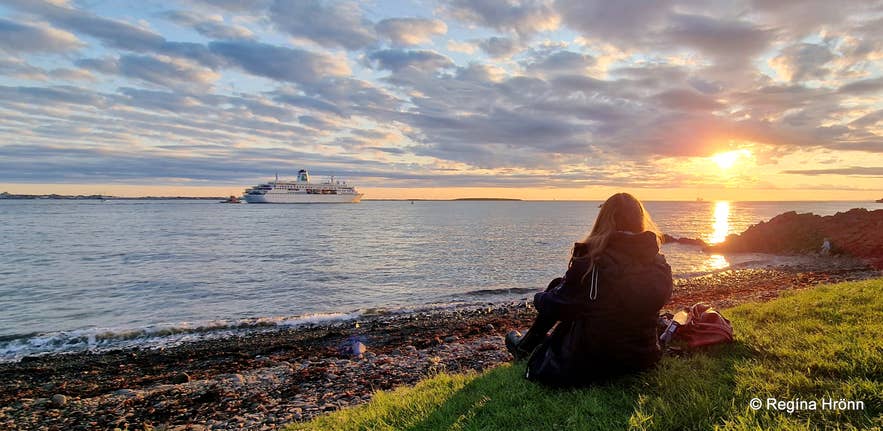 Traveler watching the midnight sun over the sea in Iceland, when daylight stretches to 21 hours in June.