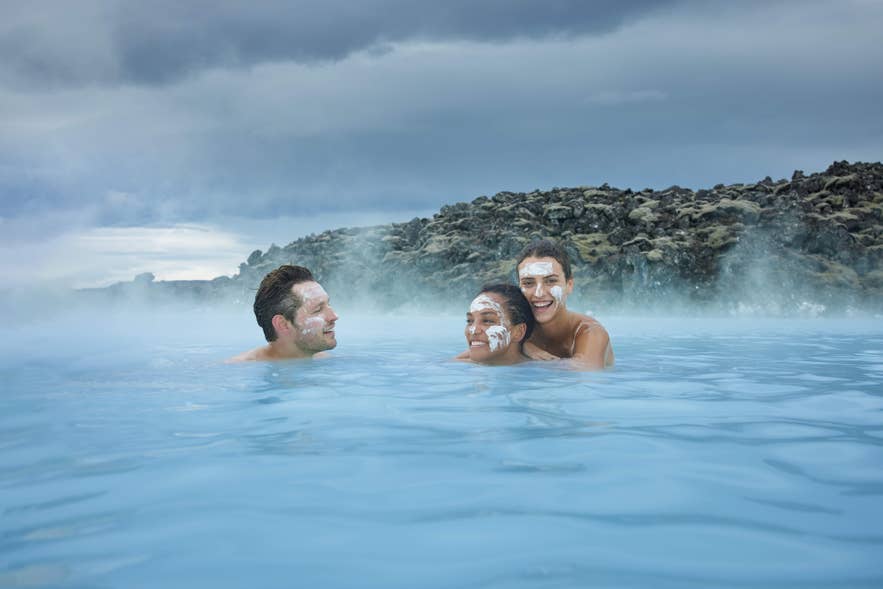 Vrienden ontspannen met silica-maskers in het warme geothermische water van de Blue Lagoon in januari in IJsland