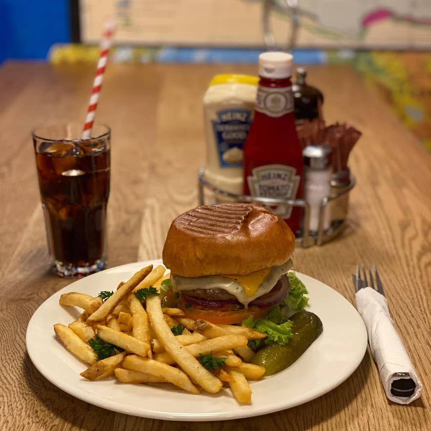 Cheeseburger with fries, pickle, and soda served at Laundromat Café in Reykjavik.