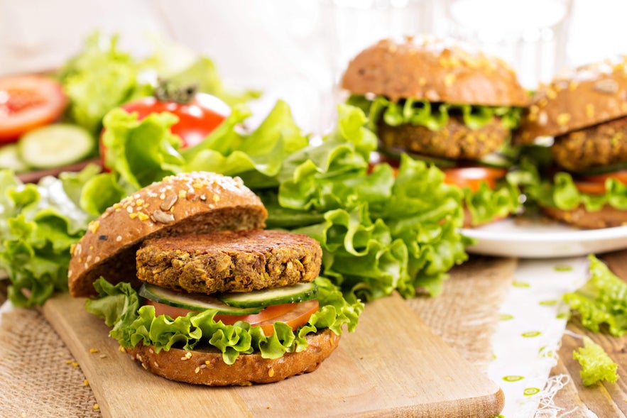Vegan burger with a plant-based patty, lettuce, cucumber, and tomato on a whole-grain bun.
