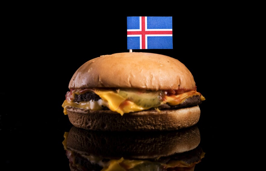 Cheeseburger with melted cheese and pickles topped with an Icelandic flag, symbolizing Reykjavik’s famous burger scene.