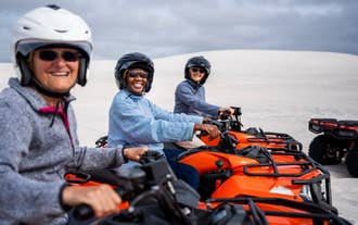 Three tourists on orange quad bikes pose for a photo on a snowy field on a Husafell quad bike tour.