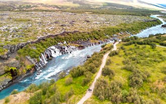 Hraunfossar Waterfalls in West Iceland, with streams of clear water flowing from lava fields into a blue river.