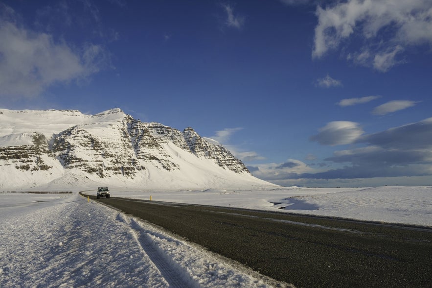 A 4x4 vehicle driving on an Icelandic highway, surrounded by snowy landscapes in November.
