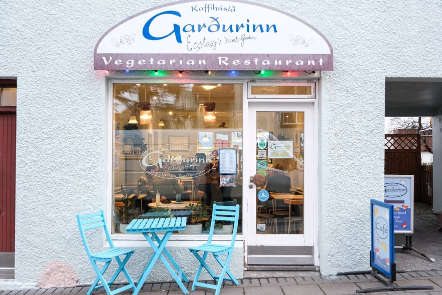 Entrance to Kaffihusid Gardurinn in Reykjavik with blue facade, outdoor seating, and vegetarian signage.