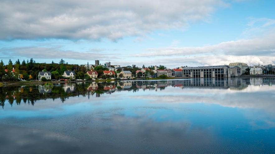 Tjornin pond in Reykjavik with birdlife under a blue sky.