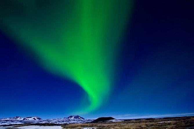 The northern lights produce a dazzling painting of green amid a bright blue night sky.