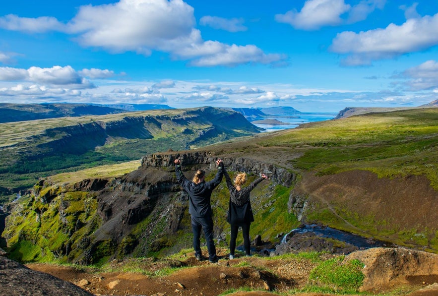 People at the top of Glymur waterfall hike with view over Hvalfjordur where Hvammsvik Hot Springs are located