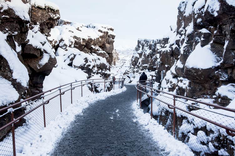A winter scene in Thingvellir National Park shows a path where people can walk between the North American and Eurasian tectonic plates.