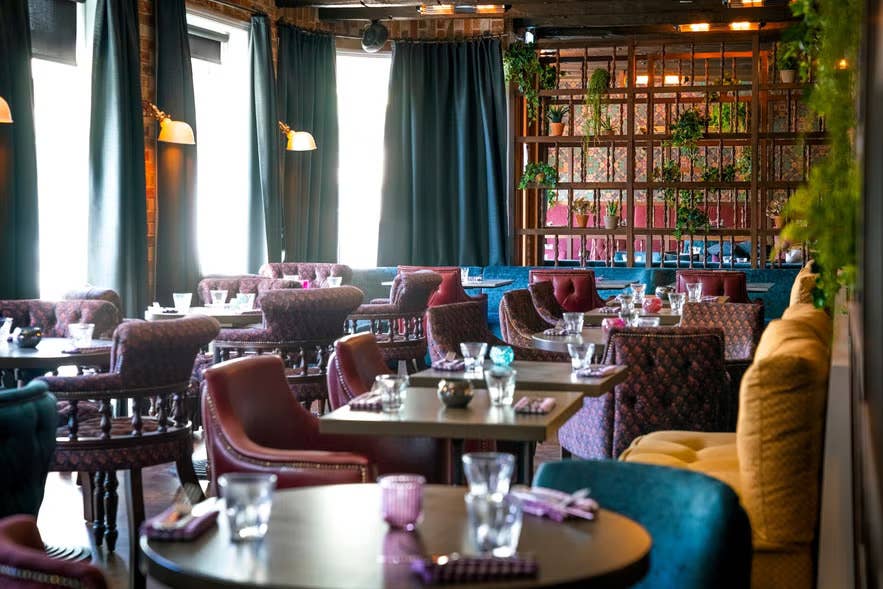 Fargerikt interiør på Fjallkonan Restaurant med polstrede stoler, blomstrete tapet og islandsk borddekking.