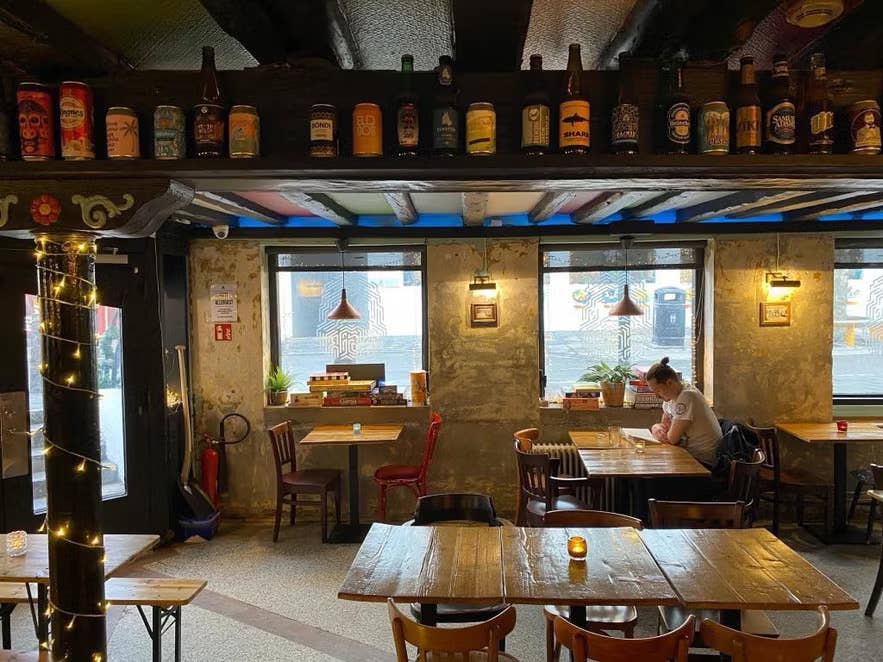 Taproom van ÆGIR 101 in het centrum van Reykjavik met rustieke inrichting, houten tafels en uitgestalde IJslandse bierflessen.