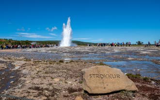 Strokkur Geyser erupts with a crowd watching during the Golden Circle tour in Iceland.